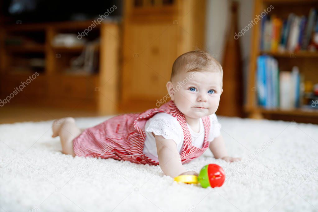 Cute baby playing with colorful rattle education toy. Lttle girl looking at the camera and crawling. Family, new life, childhood, beginning concept. Baby learning grab.