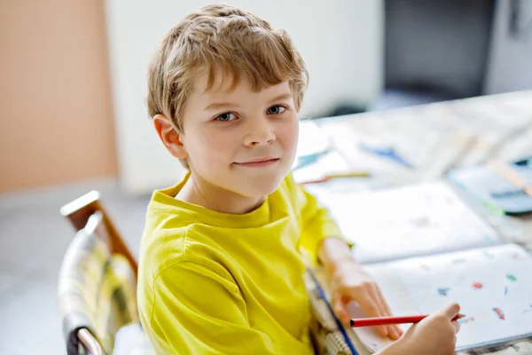 かわいい学校の子供は自宅少年の肖像画は、宿題を作る。少しは、カラフルな鉛筆、屋内と書く子が集中しています。小学校と教育。文字と数字を書く子供の学習. — ストック写真