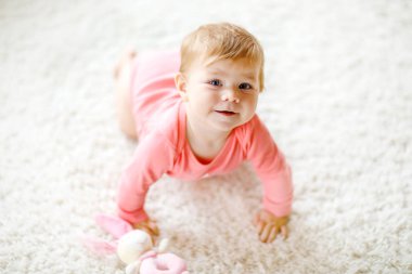 Küçük şirin bebek kız tarama öğrenme. Sağlıklı çocuk çocuk odası renkli oyuncaklar ile kaynıyor. Bebek bacakları arkadan görünüm. Ana sayfa keşfetmek ve farklı becerileri öğrenme şirin bebek