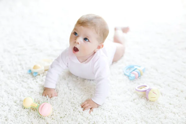 Söt baby leker med färgglada pastell vintage skallra leksak. Nyfött barn, liten flicka som tittar på kameran och kryper. Familj, nytt liv, barndom, begynnelsekoncept. Babyinlärning. — Stockfoto
