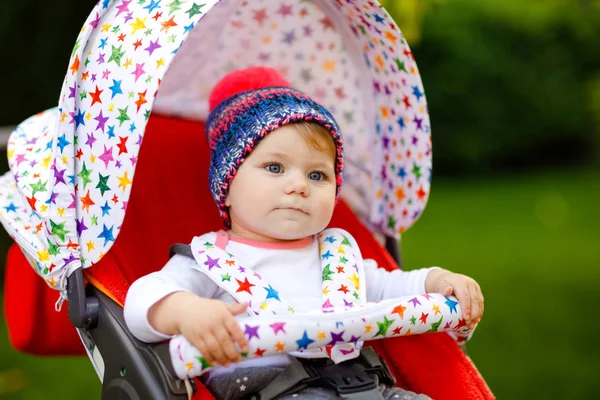 可爱的漂亮的小女孩，戴着蓝色的温暖的帽子坐在婴儿车或婴儿车里等妈妈。蓝眼睛的快乐微笑的孩子。小女儿和家人一起出去散散步 — 图库照片