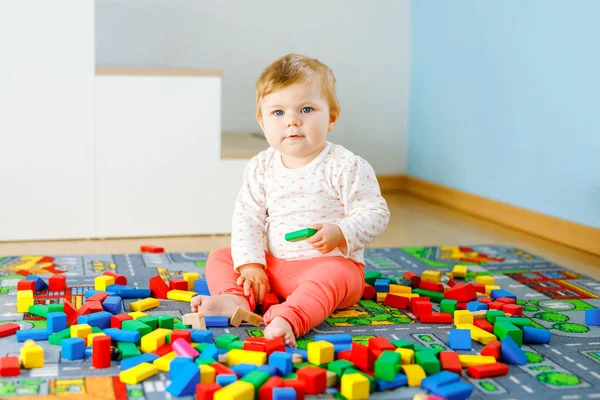 Schattig meisje dat met educatief speelgoed speelt. Gelukkig gezond kind hebben plezier met kleurrijke verschillende houten blokken thuis in de huiselijke kamer. Baby leren kleuren en vormen — Stockfoto