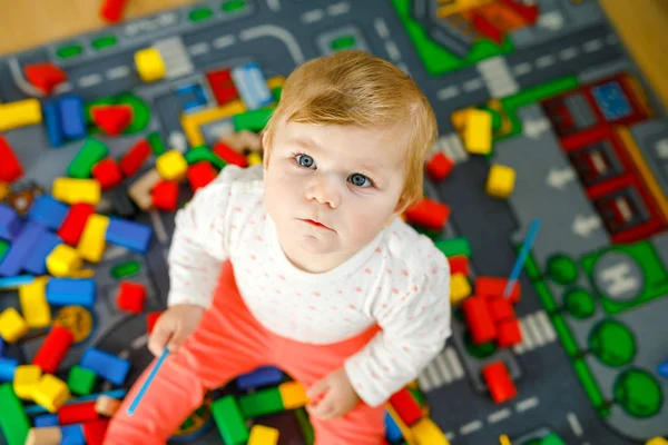 Entzückendes kleines Mädchen, das mit Lernspielzeug spielt. Glückliches gesundes Kind, das mit bunten Holzklötzen zu Hause im häuslichen Raum Spaß hat. Baby lernt Farben und Formen — Stockfoto