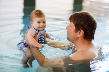 Mutlu orta yaşlı baba girdap havuzunda sevimli küçük kızıyla yüzüyor. Gülümseyen baba ve küçük çocuk, 6 aylık kız birlikte eğleniyor. Aktif aile, spa otelinde vakit geçiriyor.