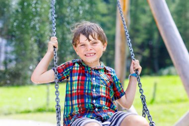Açık sahada yağmur sırasında eğlenmek zinciri salıncak ile komik çocuk çocuk. sıcak yaz günü yağmurlu sallanan çocuk. Etkin boş çocuklarla. Yağmur damlaları yüzüne ile mutlu çocuk.