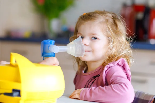 En liten flicka som andas in med nebulisator hemma. Far eller mor hjälper och håller i apparaten. Barn som har influensa, hosta och bronkit. koncept för ångsjuka astmainhalatorer — Stockfoto