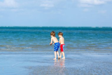 İki küçük çocuklar dostluk kavramı eğleniyor tropik sahilde oynarken, mutlu arkadaşlarım çocuğu. Kardeş kardeş, İkizler aile arka plan üzerinde avuç içi ile bak. Okyanus üzerinde aile tatil.