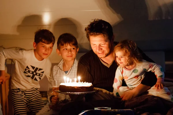 Három gyermek, kisgyermek lány és két iskolás gyerek fiú gratulálni apja a születésnapjára. Baby húga gyermek, két testvér és apa torta fúj gyertyák. Boldog egészséges családi portré — Stock Fotó