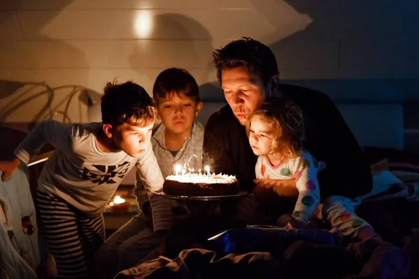 Three children, toddler girl and two school kids boys congratulating father to his birthday. Baby sister child, two brothers and dad with cake blowing candles. Happy healthy family portrait — Stock Photo, Image