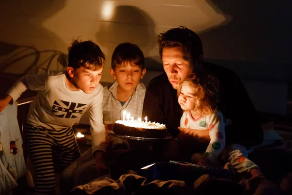 Three children, toddler girl and two school kids boys congratulating father to his birthday. Baby sister child, two brothers and dad with cake blowing candles. Happy healthy family portrait — Stock Photo, Image