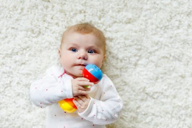 Renkli çıngıraklı oyuncakla oynayan tatlı bir kız.