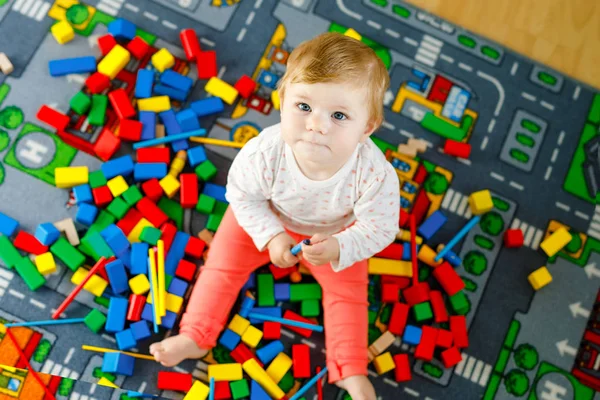 Urocza dziewczynka bawiąca się zabawkami edukacyjnymi. Szczęśliwe zdrowe dziecko bawiące się kolorowe różne drewniane klocki w domu w pokoju domowym. Baby uczenia się kolorów i form — Zdjęcie stockowe