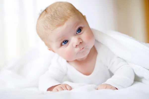 Babymädchen mit weißem Handtuch oder Wintermantel im weißen, sonnigen Schlafzimmer — Stockfoto