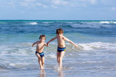 Okyanus plaj üzerinde çalışan iki çocuk çocuklar. Küçük çocuklar eğleniyor
