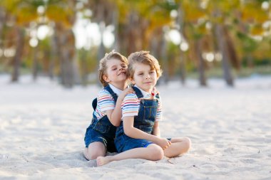 İki küçük çocuk tropik sahilde eğleniyor.