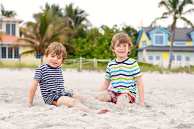 İki küçük bina kum kale ile eğleniyor tropikal kumsalda çocuklar çocuk