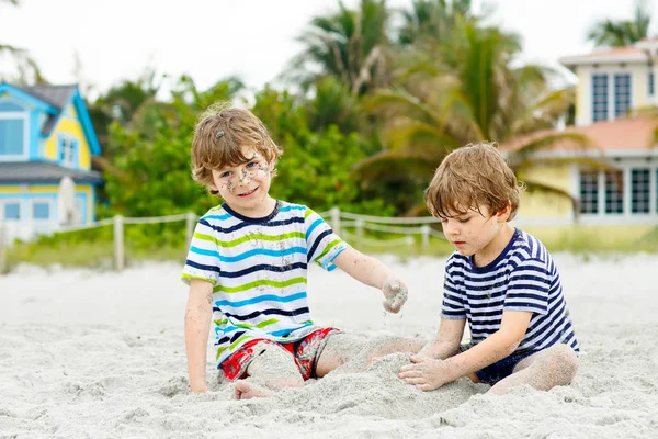 İki küçük çocuk tropik sahilde eğleniyor.