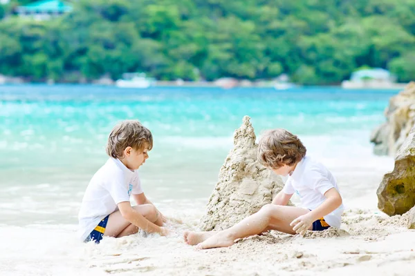 Двоє хлопчиків будують піщаний замок на тропічному пляжі — стокове фото