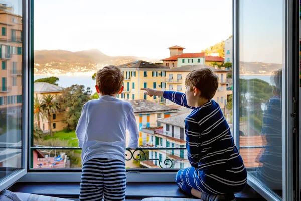 Dos niños pequeños disfrutando de la vista desde la ventana de la mañana en la región de Liguria en Italia. Impresionantes pueblos de Cinque Terre y Portofino. Vacaciones en familia en la hermosa ciudad italiana con casas coloridas . — Foto de Stock