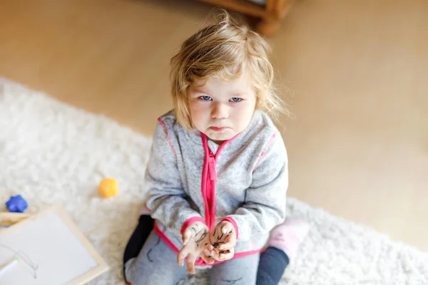 Triest huilen peuter meisje leren schilderen met viltstiften. Het kleine baby kind tekent op handen en kleren. Boos kind in hysterische crisis als ouders schreeuwen met dochter voor vuile handen. — Stockfoto