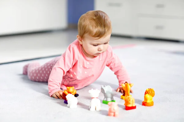 Adorable baby girl playing with domestic toy pets like cow, horse, sheep, dog and wild animals like giraffe, elephant and monkey. Happy healthy child having fun with colorful different toys at home — Stock Photo, Image