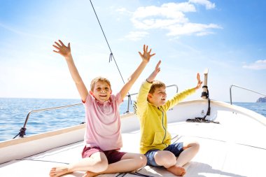 İki küçük çocuk, en iyi arkadaşlar yelkenli tekne gezisi zevk. Güneşli bir günde okyanus ta denizde aile tatilleri. Çocuklar gülümsüyor. Kardeşler, okul childen, kardeşler yatta eğleniyor.