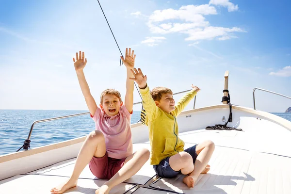 Двоє маленьких хлопчиків, найкращі друзі насолоджуються подорожжю на човні. Сімейні канікули на океані або морі в сонячний день. Діти посміхаються. Брати, школярки, брати і сестри розважаються на яхті . — стокове фото