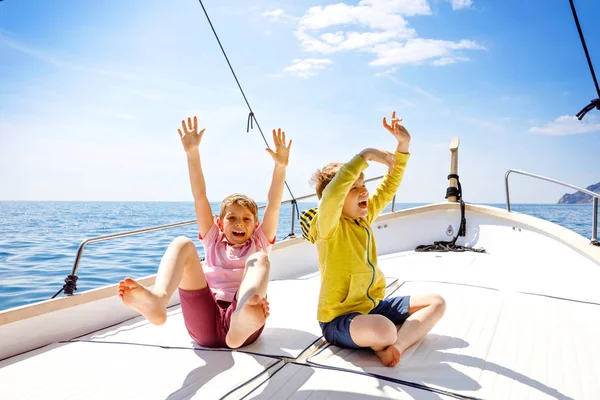 Двоє маленьких хлопчиків, найкращі друзі насолоджуються подорожжю на човні. Сімейні канікули на океані або морі в сонячний день. Діти посміхаються. Брати, школярки, брати і сестри розважаються на яхті . — стокове фото