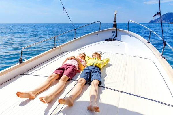 Two little kid boys, best friends enjoying sailing boat trip. Family vacations on ocean or sea on sunny day. Children smiling. Brothers, schoolchilden, siblings having fun on yacht. — Stock Photo, Image