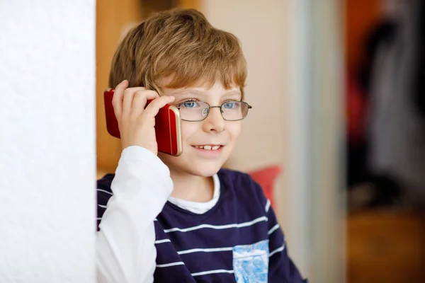 En söt liten pojke med glasögon som talar i mobiltelefon. Bedårande friska barn som håller smartphone och prata med en flicka vän eller med föräldrar, morföräldrar. — Stockfoto