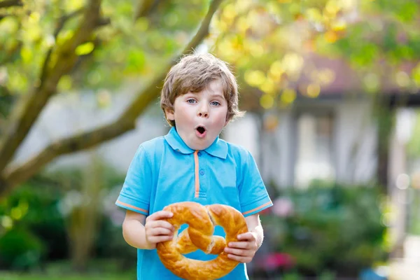 Adorabile bambino ragazzo mangiare enorme grande bavarese tedesco pretzel. — Foto Stock