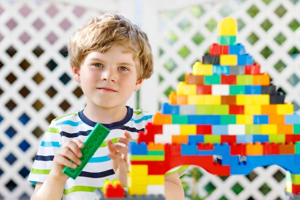 Pequena criança loira e garoto brincando com muitos blocos de plástico coloridos. — Fotografia de Stock