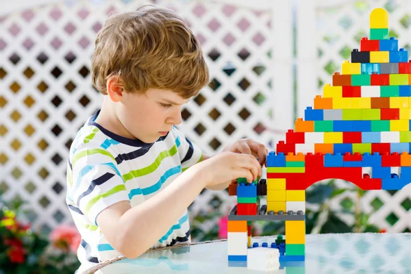 Niño rubio y niño jugando con un montón de bloques de plástico de colores. —  Fotos de Stock
