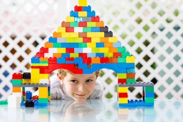 Klein blond kind en kind jongen spelen met veel kleurrijke plastic blokken. — Stockfoto