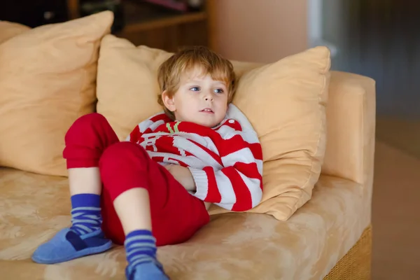 Gelukkig schattig kind jongen televisiekijken liggend. Grappige gezond kind genieten van tekenfilms. Verslaving concept. Peuter op zoek shows en film op tv thuis. — Stockfoto