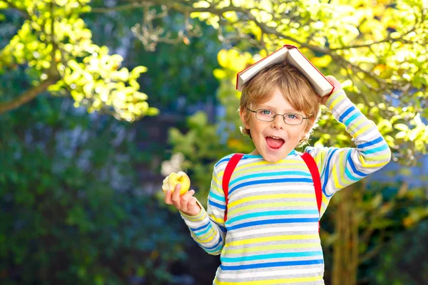 Niño preescolar feliz con gafas, libros, manzana y mochila en su primer día de escuela o guardería. Divertido niño sano al aire libre en un día cálido y soleado, concepto de regreso a la escuela. Chico sonriente. —  Fotos de Stock