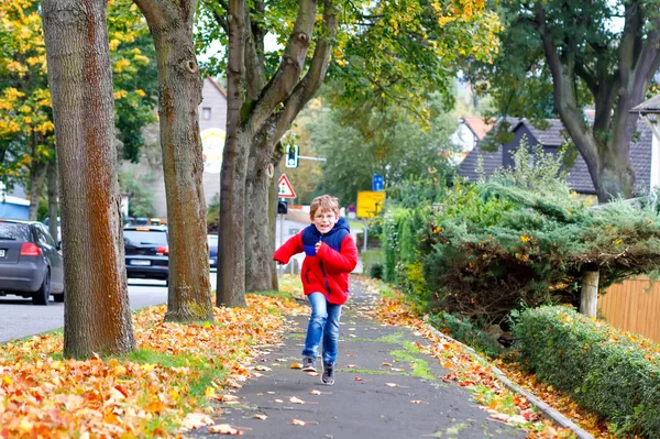 Okuldan sonra Autumnal caddesinde koşan küçük mutlu çocuk. Çocuk okul tatillerinden memnun. Sonbahar moda elbiseli çocuk gözlük takıyor. — Stok fotoğraf