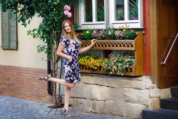 Schöne junge Frau mit langen Haaren im Sommerkleid, die in deutschen Städten spazieren geht. Glückliches Mädchen genießt Spaziergänge in netter Kleinstadt mit alten Häusern in Deutschland. — Stockfoto