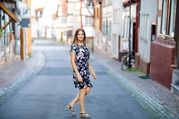 Hermosa joven con cabellos largos en vestido de verano que va a dar un paseo por la ciudad alemana. Chica feliz disfrutando de caminar en la pequeña ciudad linda fachwerk con casas antiguas en Alemania. —  Fotos de Stock