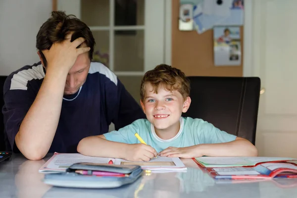 Un ragazzino carino a casa a fare i compiti con papa '. Bambino che scrive con matite colorate, padre che lo aiuta, in casa. Scuola elementare e istruzione. — Foto Stock