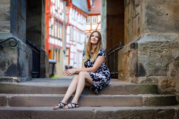 Belle jeune femme aux cheveux longs en robe d'été se promenant dans la ville allemande. Fille heureuse profitant de la marche dans une jolie petite ville fachwerk avec de vieilles maisons en Allemagne. — Photo