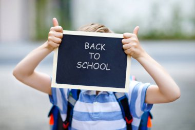 Happy little kid boy with backpack or satchel. Schoolkid on the way to school. Healthy adorable child outdoors With chalk desk for copyspace. Back to school or schools out. Unrecognizable face clipart