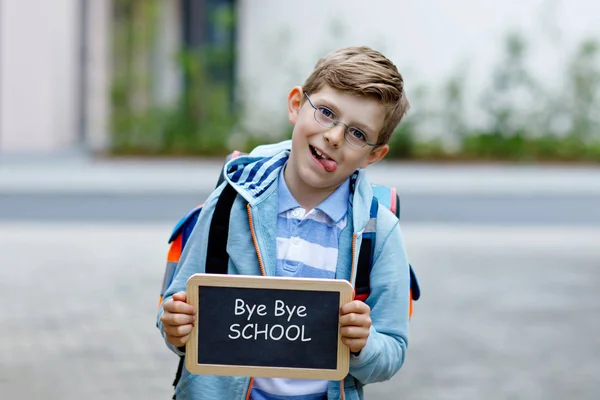 Glücklicher kleiner Junge mit Rucksack oder Schulranzen und Brille. Schulkind auf dem Schulweg. Gesundes liebenswertes Kind draußen auf dem Kreidetisch Tschüss Schule. zurück zum Schulkonzept — Stockfoto