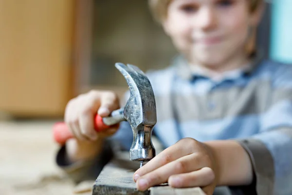 Little kid boy helping with toy tools on construction site. Funny child of 6 years having fun on building new family home. Kid with nails and hammer helping father to renovate old house.