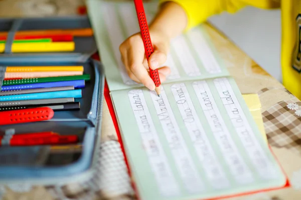 Lose-up of little kid boy at home making homework, child writing first letters and words like mama with colorful pens. Elementary school and education — Stock Photo, Image