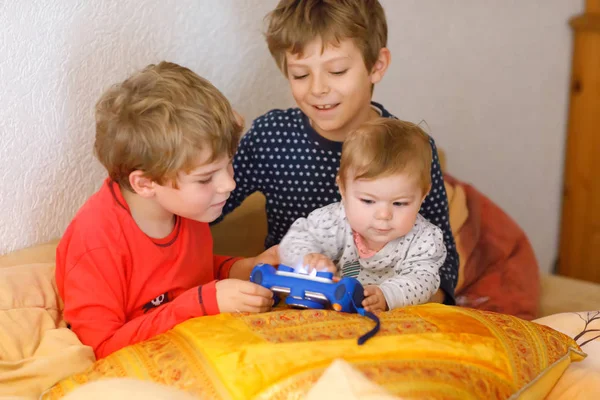 Två förskola eller skola kids pojkar, syskon och bröder och liten flicka baby girl ha kul efter skoldag spela video spel hemma och ta bilder med Toy Camera. — Stockfoto