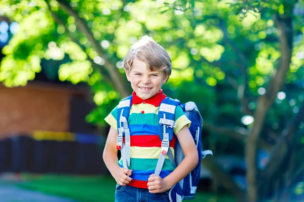 Glücklicher kleiner Junge in buntem Hemd und Rucksack oder Schulranzen an seinem ersten Schul- oder Kindergartentag. Kind an warmen, sonnigen Tagen im Freien, zurück zum Schulkonzept. Junge in bunter Uniform. — Stockfoto