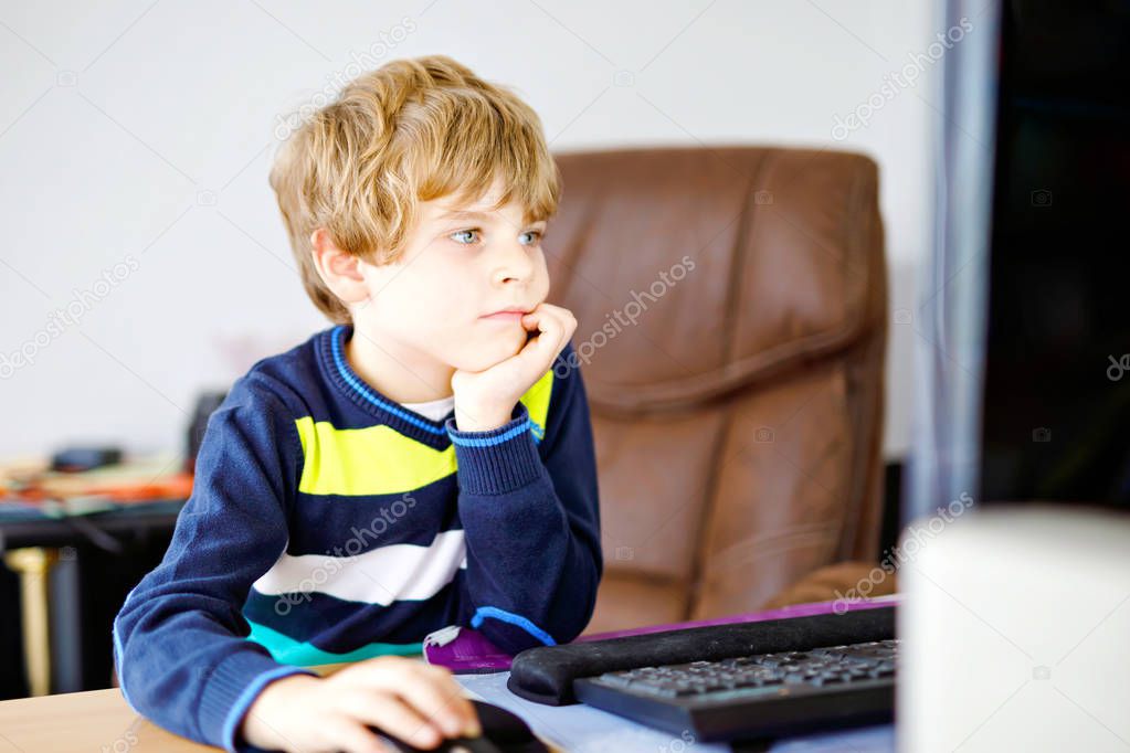 Little kid boy making school homework on computer notebook. Happy healthy child searching information on internet. New media education, kid watching learning lessons on pc. Virtual classroom.