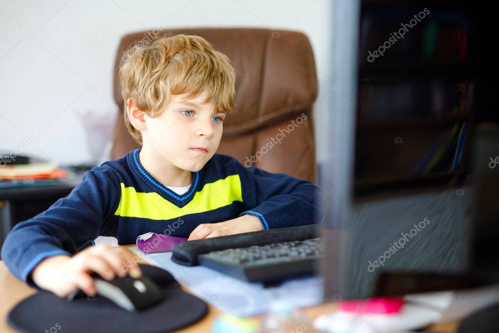 Little kid boy making school homework on computer notebook. Happy healthy child searching information on internet. New media education, kid watching learning lessons on pc. Virtual classroom.