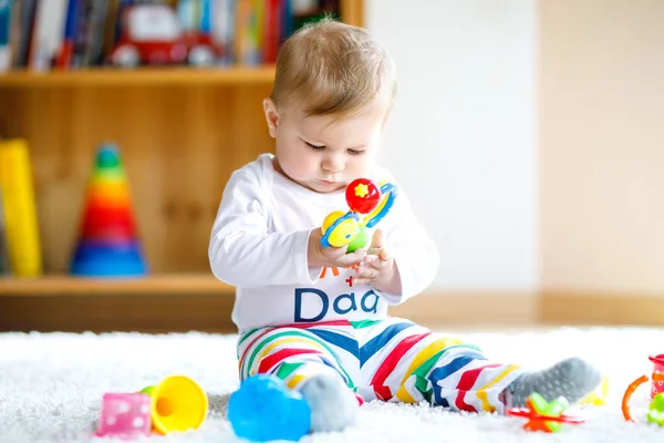 Adorable baby girl playing with educational toys in nursery. Happy healthy child having fun with colorful different toys at home. Baby development and first steps, learning to play and to grab. — Stock Photo, Image